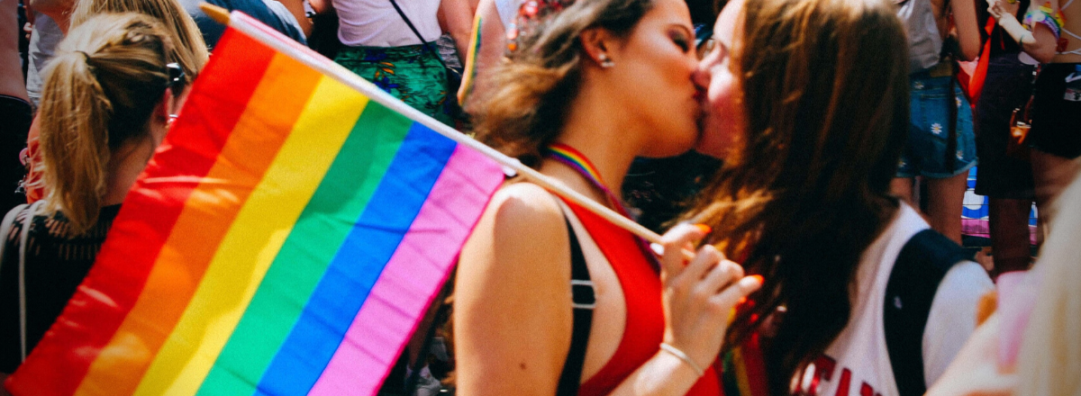 to piger, der kysser og holder et regnbueflag