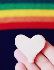 regnbue og hånd, der holder et hjerte af ler