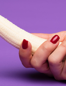 Kvindehånd, der holder en skrællet banan. Foto: Deon Black